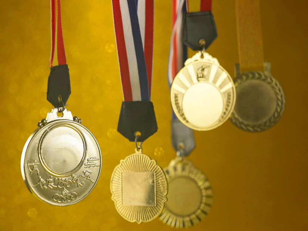 Goldmedaillen glänzen vor gelbem Hintergrund.